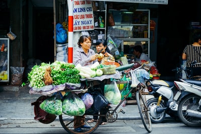 在商店附近的自行车摊上切蔬菜的女人